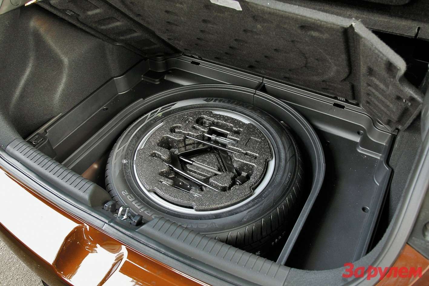 В России автомобиль комплектуется полноценной запаской, вокруг которой сделана полукруглая ниша для мелочей.